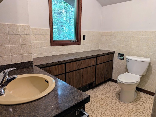 bathroom featuring vanity, tile walls, and toilet