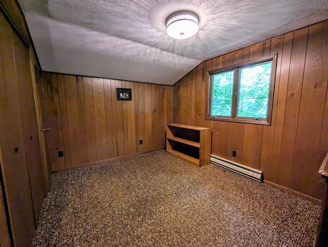 additional living space with baseboard heating, wooden walls, carpet flooring, and a textured ceiling