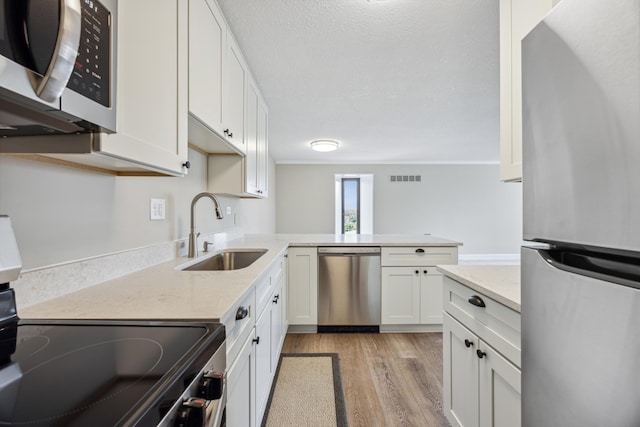 kitchen featuring sink, light hardwood / wood-style flooring, appliances with stainless steel finishes, kitchen peninsula, and white cabinets