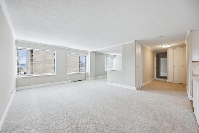 empty room featuring light carpet, ornamental molding, and a textured ceiling