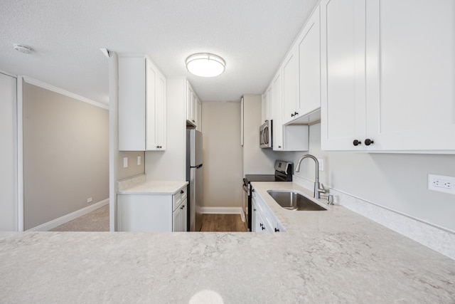 kitchen with appliances with stainless steel finishes, sink, white cabinets, and a textured ceiling