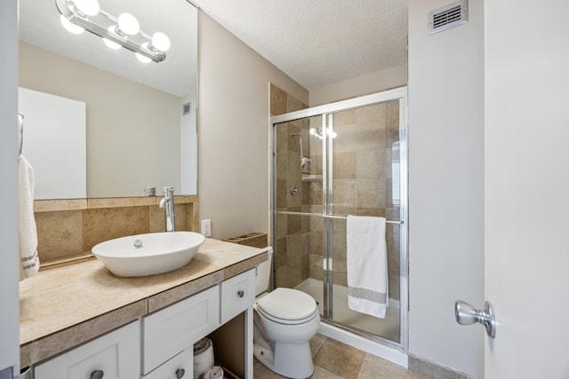 bathroom featuring vanity, an enclosed shower, a textured ceiling, and toilet