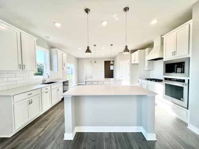 kitchen with pendant lighting, sink, premium range hood, appliances with stainless steel finishes, and white cabinets