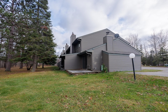 view of home's exterior with a wooden deck and a lawn