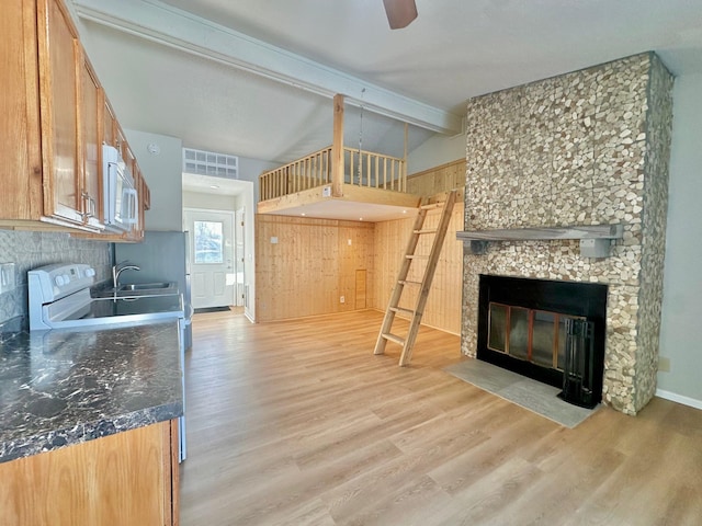 kitchen featuring white appliances, a fireplace, lofted ceiling with beams, and light wood-type flooring