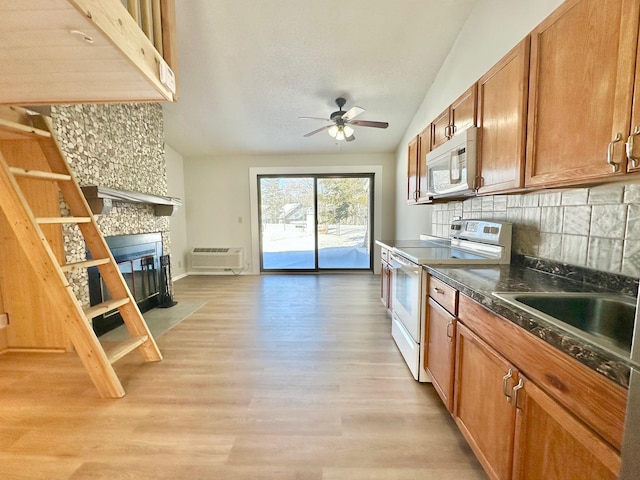 kitchen featuring sink, white appliances, a tile fireplace, decorative backsplash, and vaulted ceiling