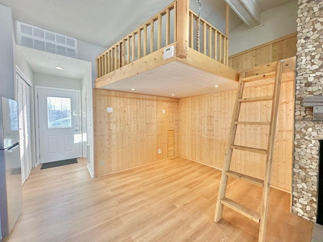 interior space featuring a fireplace, wood-type flooring, wooden walls, and a high ceiling