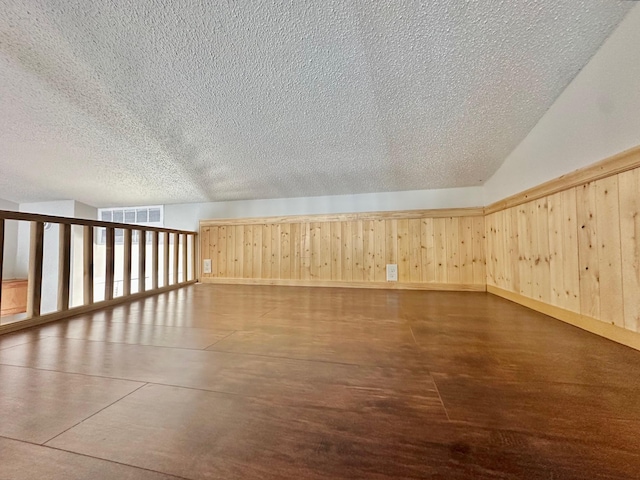 bonus room featuring wooden walls and a textured ceiling