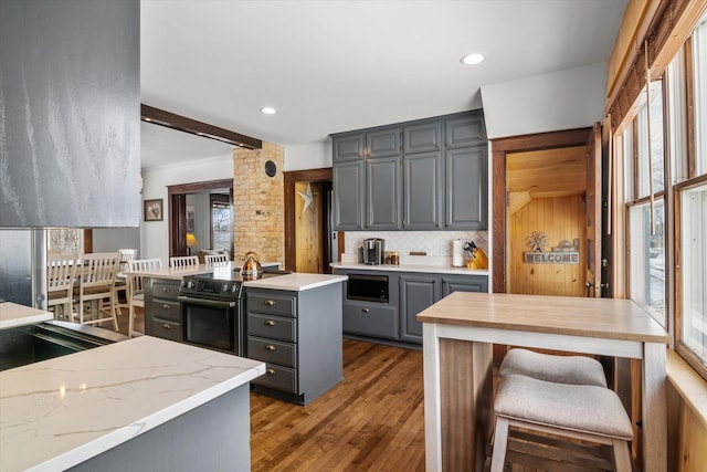 kitchen featuring built in microwave, gray cabinetry, range with electric cooktop, wood finished floors, and decorative backsplash