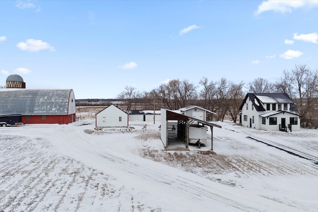 yard layered in snow with a barn, a garage, and an outbuilding