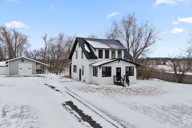 view of front of property with an outdoor structure, fence, a detached garage, and metal roof