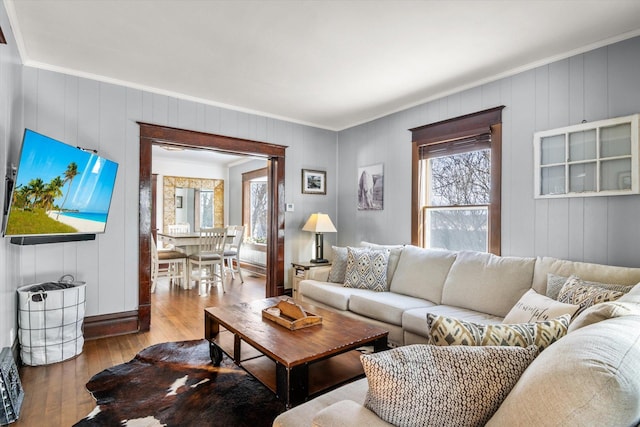 living room featuring hardwood / wood-style floors, wood walls, and ornamental molding