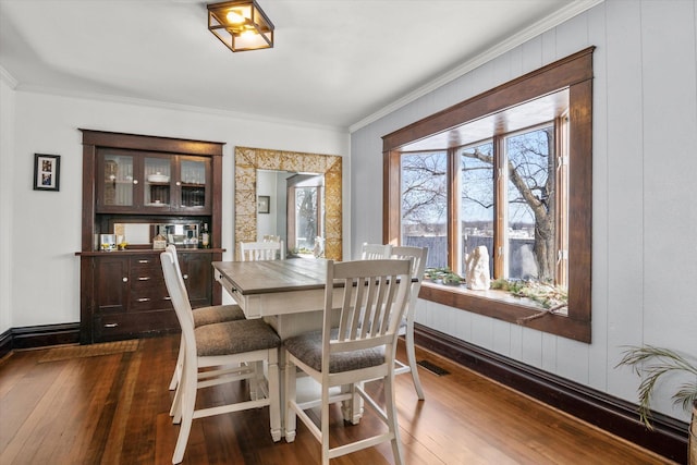 dining space featuring dark wood-style flooring, a healthy amount of sunlight, and crown molding