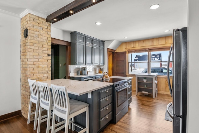kitchen featuring hardwood / wood-style flooring, crown molding, light stone countertops, and stainless steel appliances