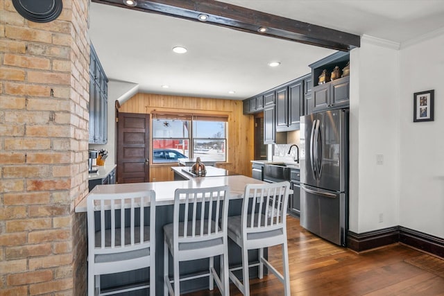 kitchen with a peninsula, dark wood-style floors, a sink, freestanding refrigerator, and light countertops