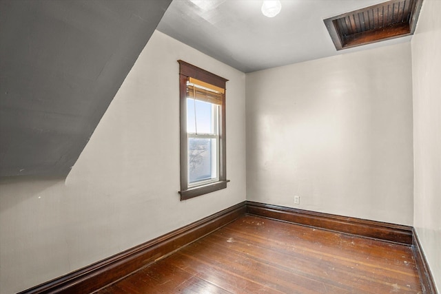 empty room featuring visible vents, attic access, baseboards, and wood-type flooring