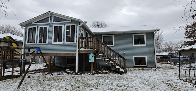 snow covered back of property with a playground