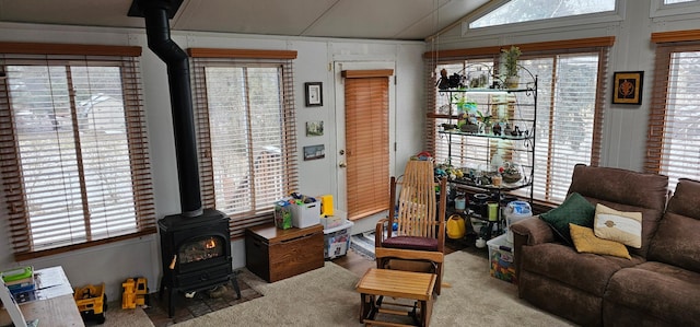 living room featuring lofted ceiling, plenty of natural light, and a wood stove