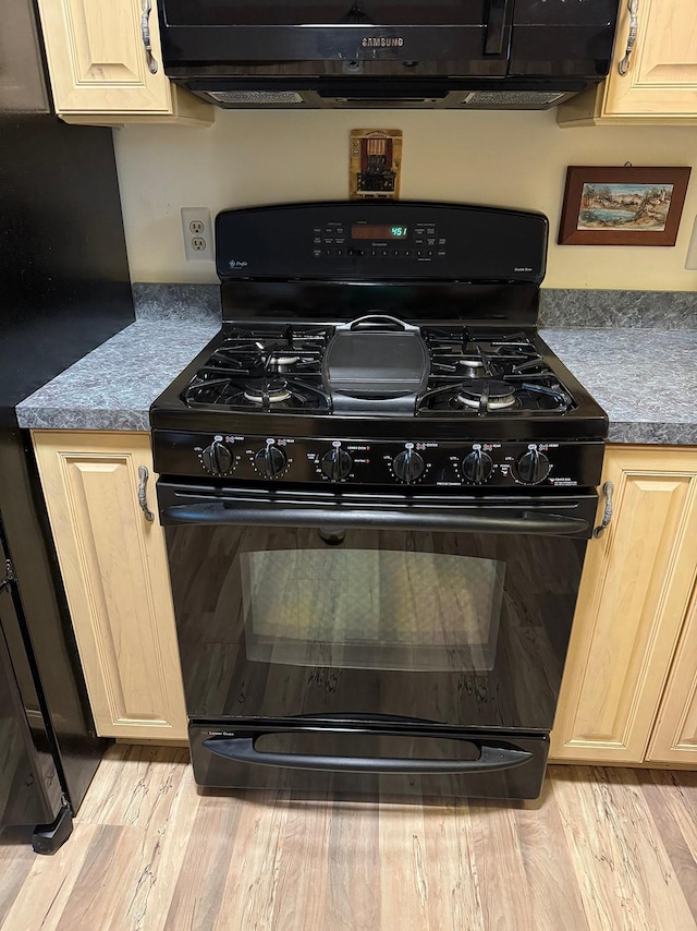 kitchen with light brown cabinetry, light hardwood / wood-style flooring, and black appliances