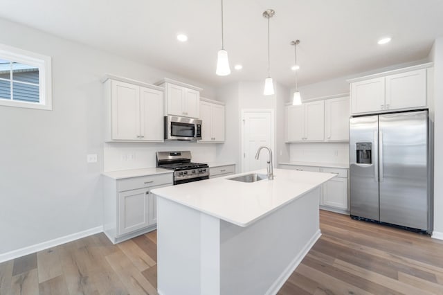 kitchen with white cabinetry, appliances with stainless steel finishes, sink, and decorative light fixtures