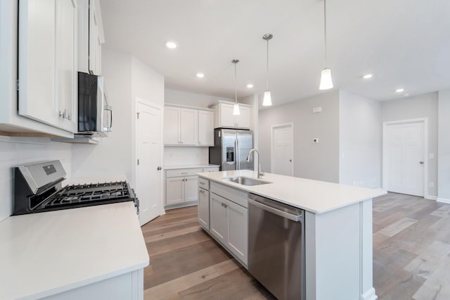 kitchen with a kitchen island with sink, sink, white cabinets, and appliances with stainless steel finishes