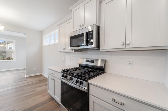 kitchen with white cabinetry, stainless steel appliances, light hardwood / wood-style floors, and decorative backsplash