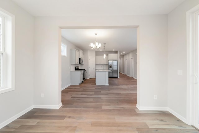 kitchen featuring a center island, hanging light fixtures, a notable chandelier, stainless steel appliances, and white cabinets