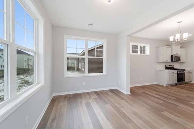 interior space with an inviting chandelier, a healthy amount of sunlight, and light wood-type flooring