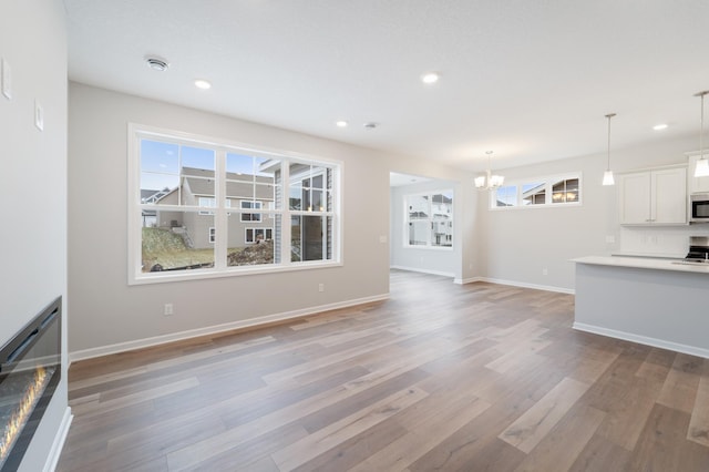 unfurnished living room featuring light hardwood / wood-style floors and a chandelier