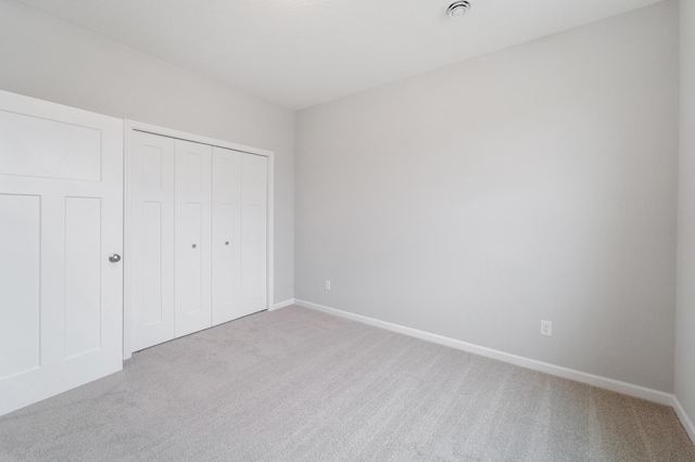 unfurnished bedroom with light colored carpet and a closet