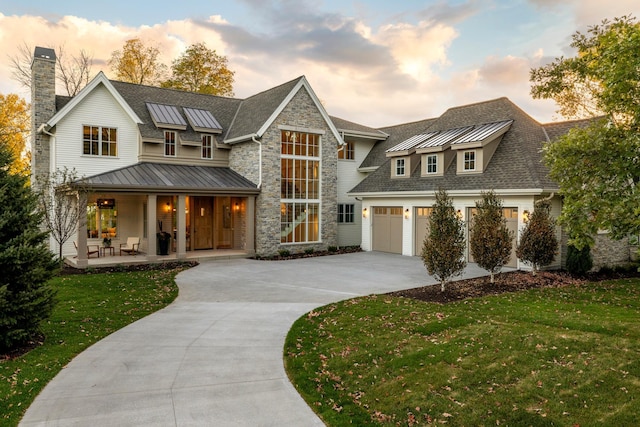 modern farmhouse style home with a garage, a porch, and a lawn