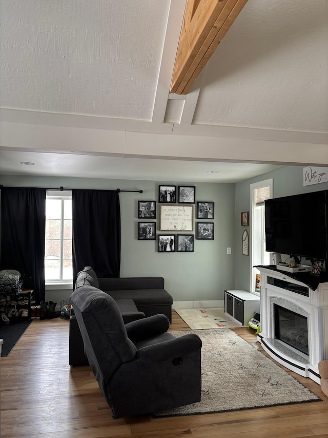 living room with beam ceiling, hardwood / wood-style flooring, and a premium fireplace