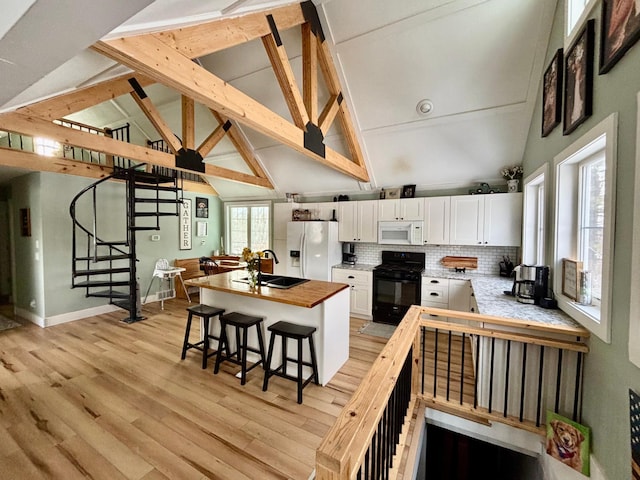 kitchen with butcher block countertops, sink, white appliances, white cabinets, and a kitchen bar