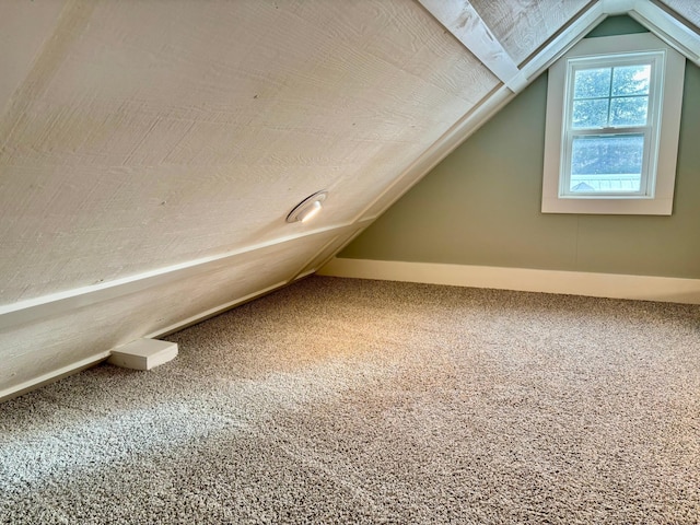 bonus room with vaulted ceiling and carpet