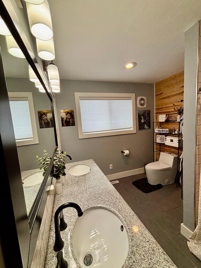 bathroom featuring vanity, wooden walls, and toilet