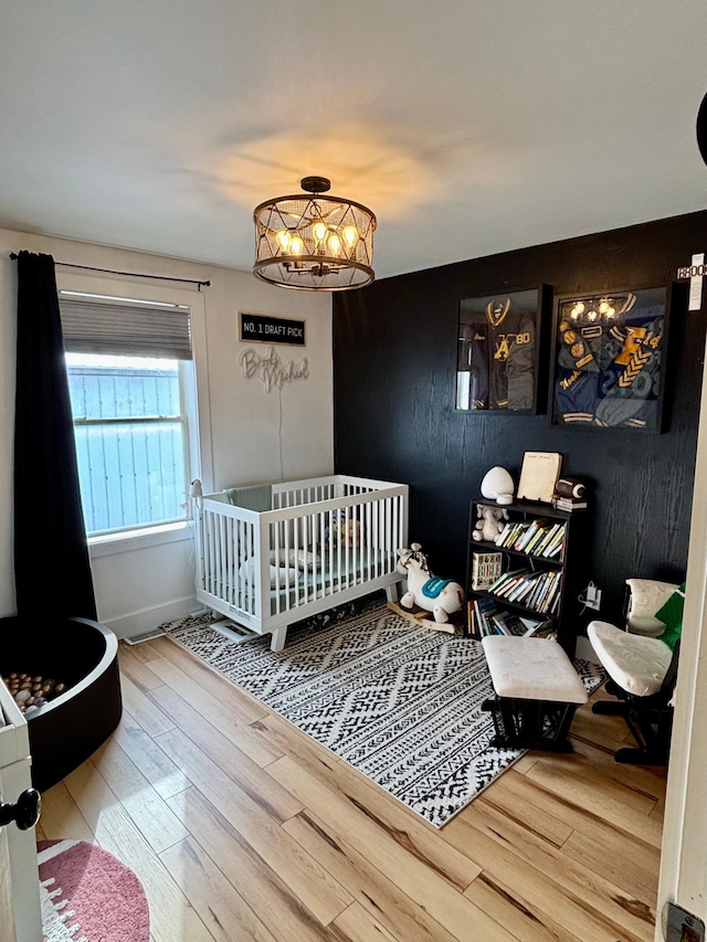 bedroom featuring wood-type flooring and a nursery area