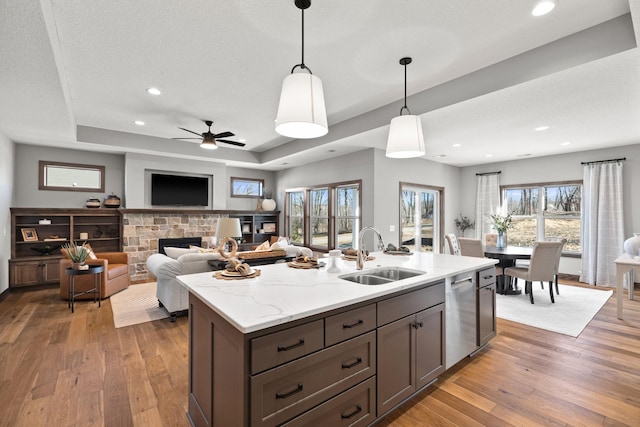 kitchen with dishwasher, a tray ceiling, sink, and decorative light fixtures