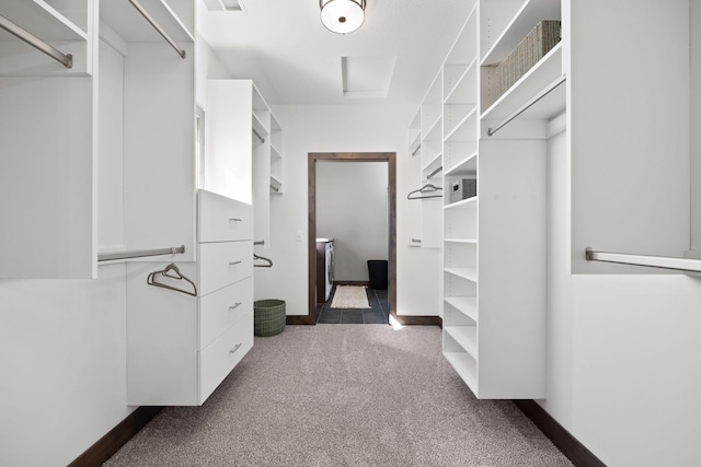 spacious closet featuring dark colored carpet and separate washer and dryer