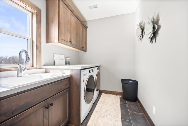 washroom featuring sink, cabinets, washing machine and clothes dryer, and dark tile patterned flooring