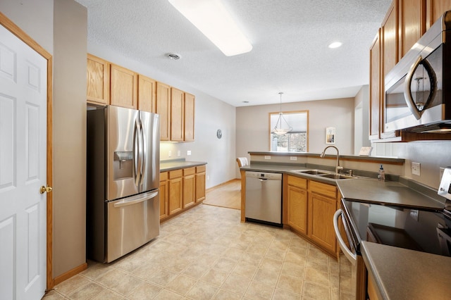 kitchen with appliances with stainless steel finishes, decorative light fixtures, sink, and a textured ceiling