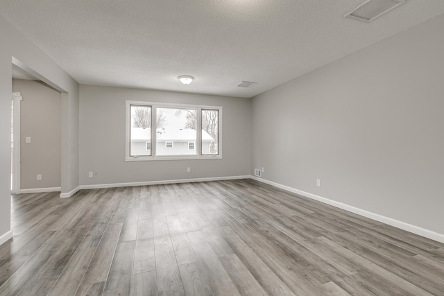 unfurnished room with light hardwood / wood-style flooring and a textured ceiling