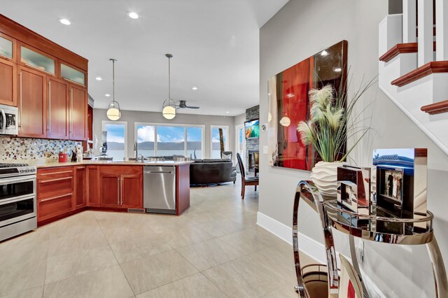 kitchen with tasteful backsplash, decorative light fixtures, light tile patterned floors, appliances with stainless steel finishes, and a fireplace