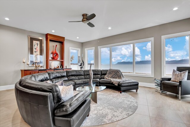 tiled living room featuring a water view and ceiling fan