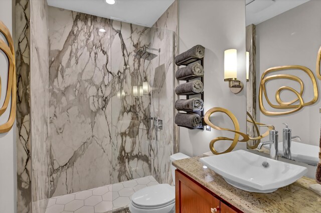 bathroom with vanity, toilet, and a tile shower