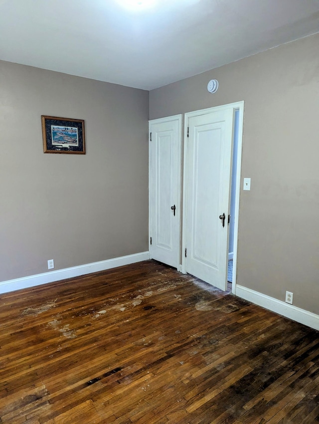 unfurnished room featuring dark wood-style floors and baseboards