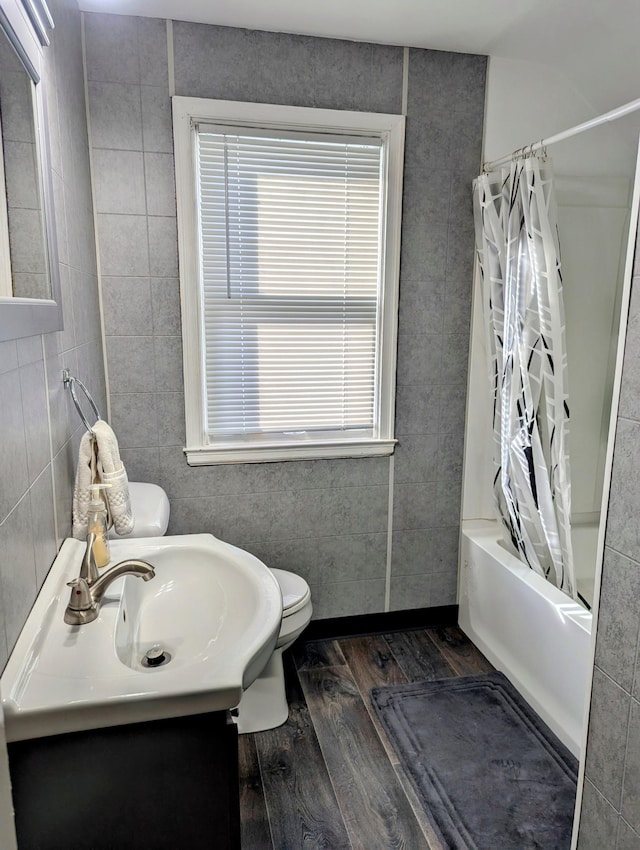 bathroom featuring shower / bathtub combination with curtain, toilet, wood finished floors, and vanity