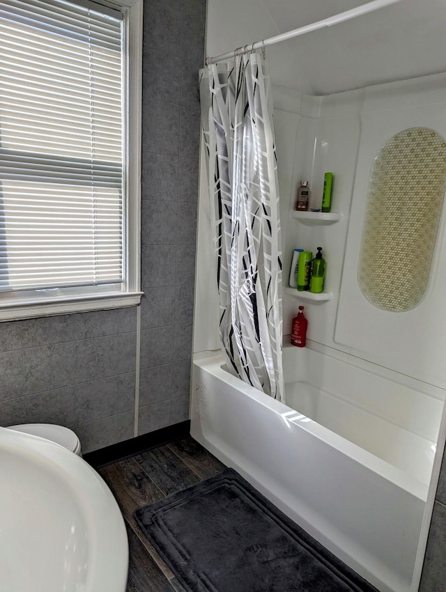 full bath with shower / tub combo with curtain and wood finished floors