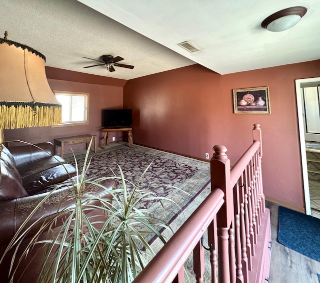 bedroom with visible vents, baseboards, wood finished floors, a textured ceiling, and a ceiling fan