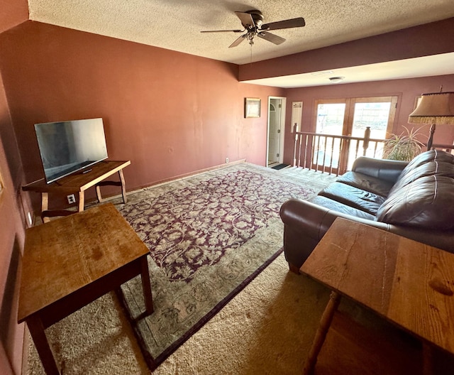 living area featuring baseboards, a textured ceiling, ceiling fan, and carpet flooring