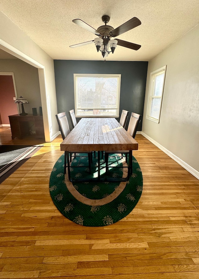 dining area with baseboards, a textured ceiling, and wood finished floors